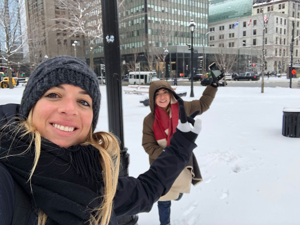 dos chicas posando para cámara y detrás el paisaje de una ciudad con nieve